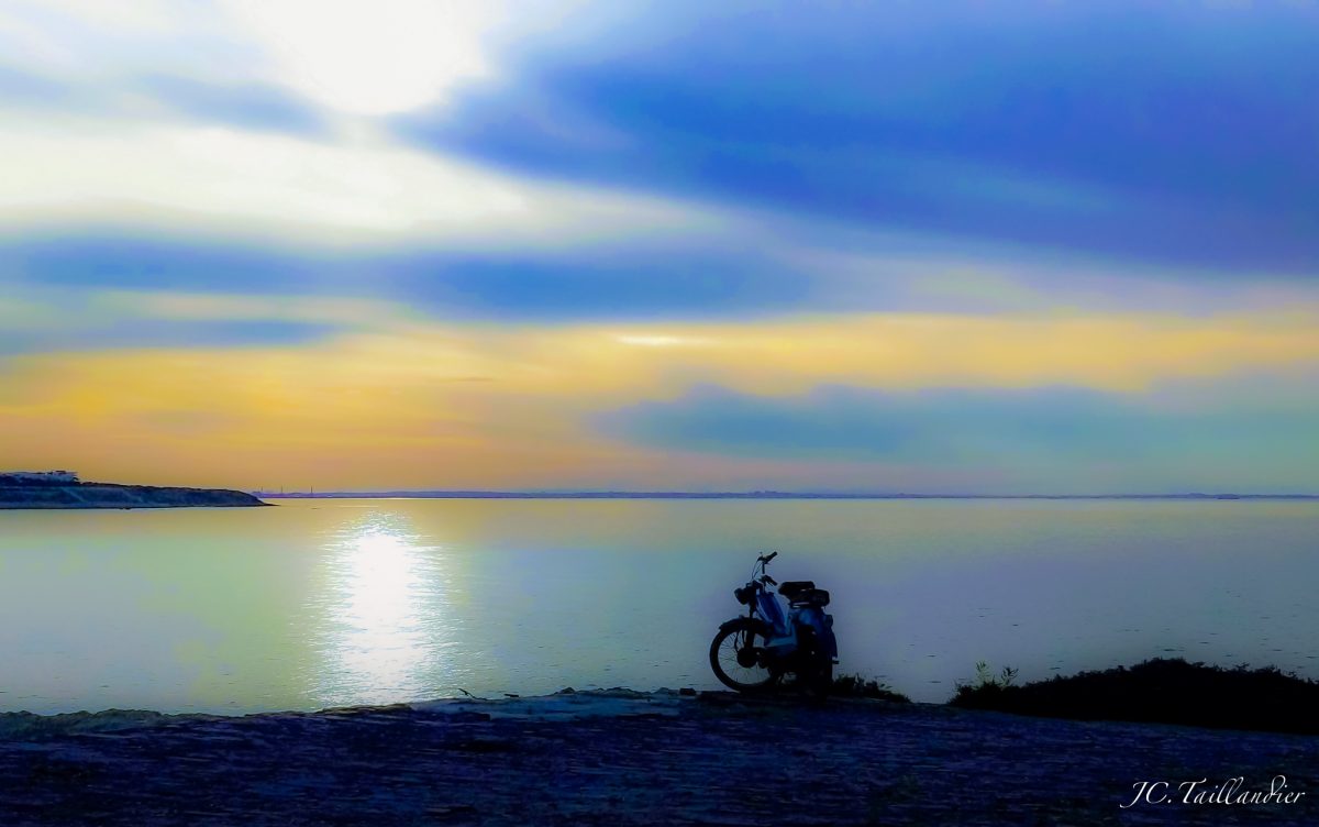 Une mobylette au bord de la mer à Monastir, qui se détache sur le soleil couchant